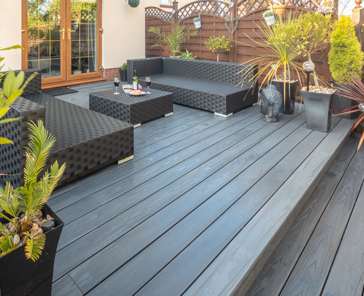 Alchemy composite decking accompanied with garden furniture and potted plants