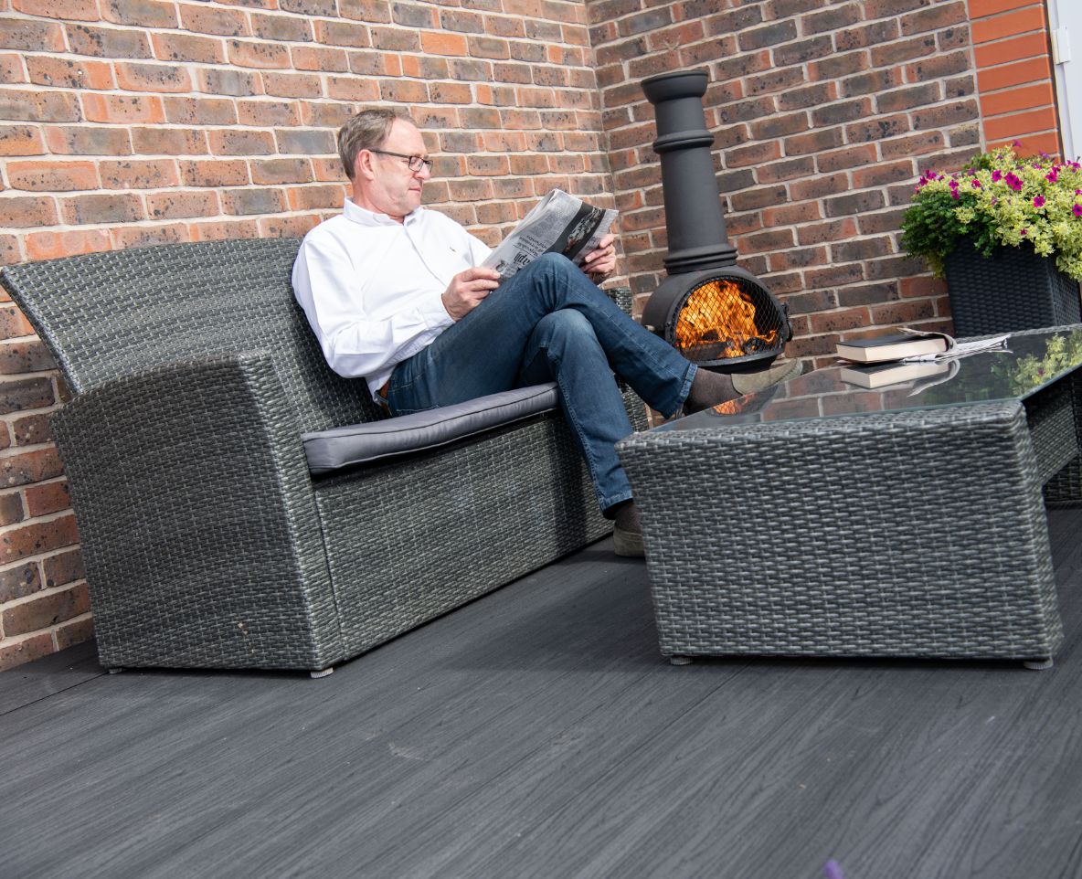 Man reading a newspaper whilst sitting on his Alchemy Habitat decking