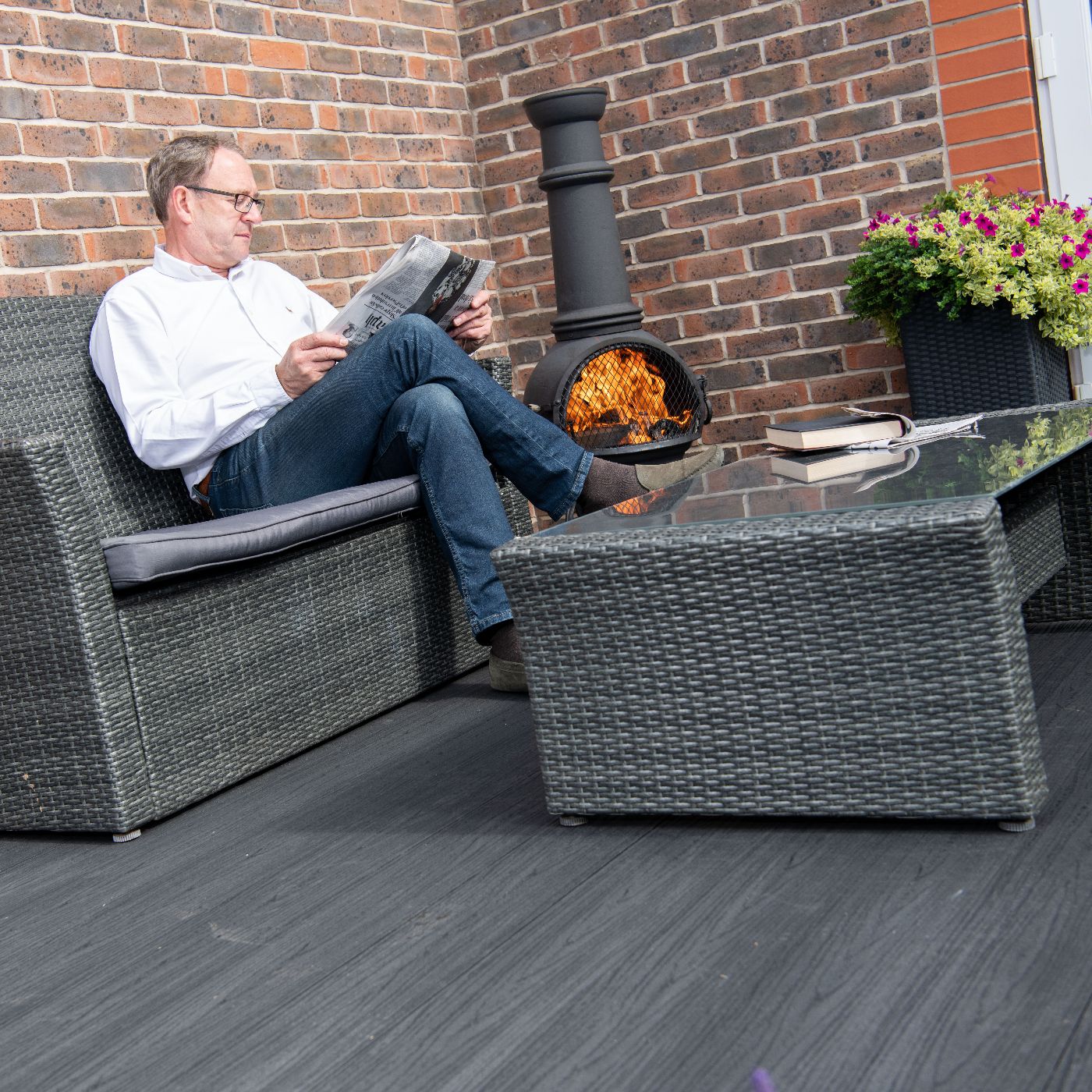 Man reading a newspaper whilst sitting on his Alchemy Habitat decking